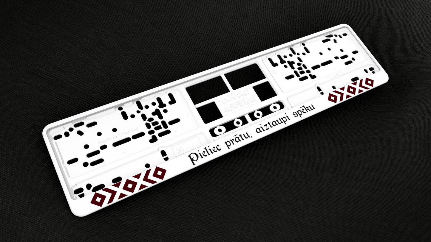 Balts auto numura turētājs ar latvju rakstiem un uzrakstu - Pieliec prātu, aiztaupi spēku Latsign